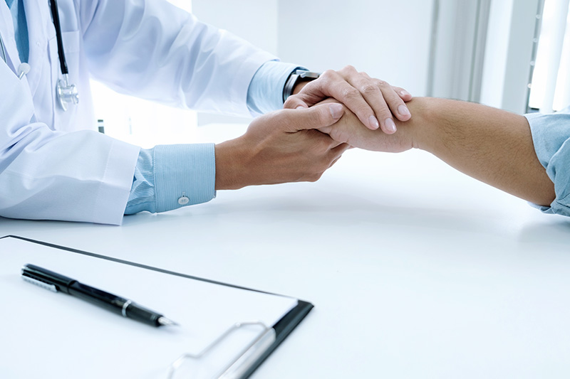 Manos de paciente, tomadas por un profesional de salud