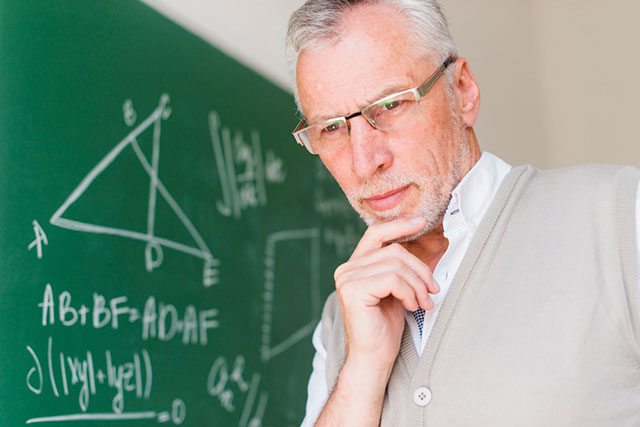 Profesor frente a un pizarrón con diversas fórmulas