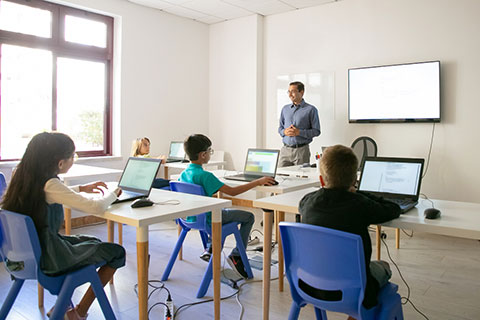 salón de clases con maestro y niños realizando actividades escolares