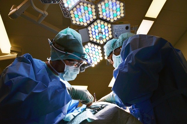 dos personas, con quirúrgico y en un quirófano, realizando un procedimiento