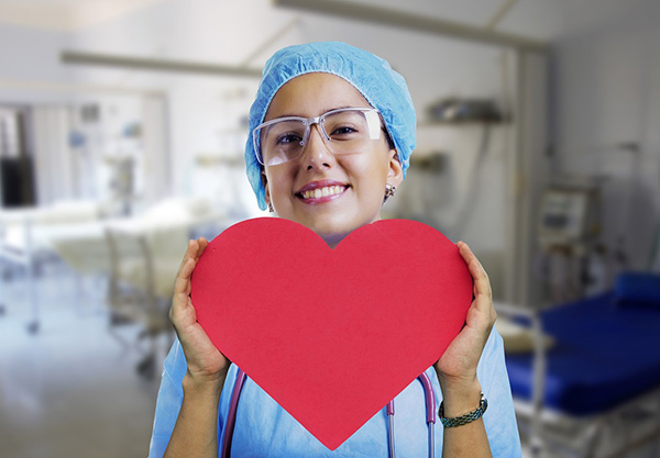 Enfermera sonriendo y sosteniendo la imagen de un corazón.