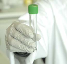 Fotografía de laboratorista sosteniendo muestra en tubo.