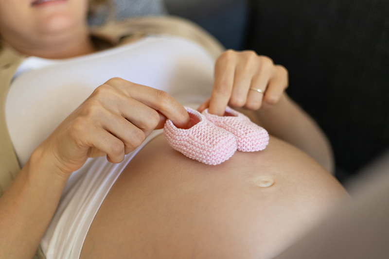Mujer embarazada y objetos femeninos para bebé.