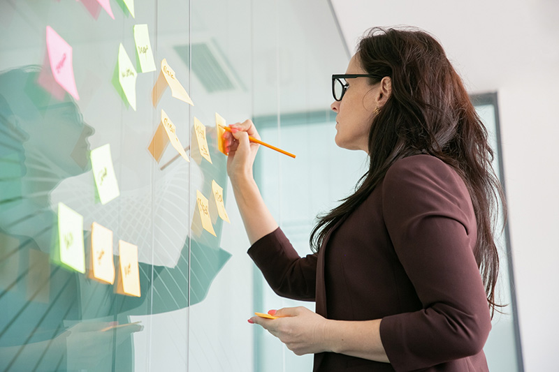 Mujer realizando anotaciones en post-it Mujer realizando anotaciones en post-it