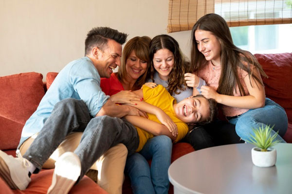 familia sentada en un sillón jugando con sus hijos