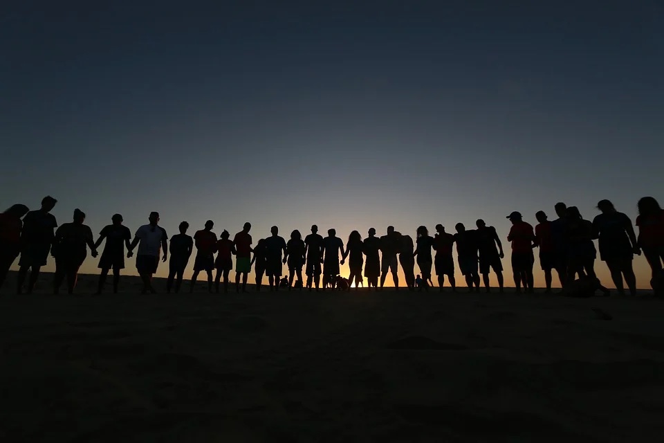 grupo de amigos en la playa contemplan la puesta de sol tomados de la mano” 