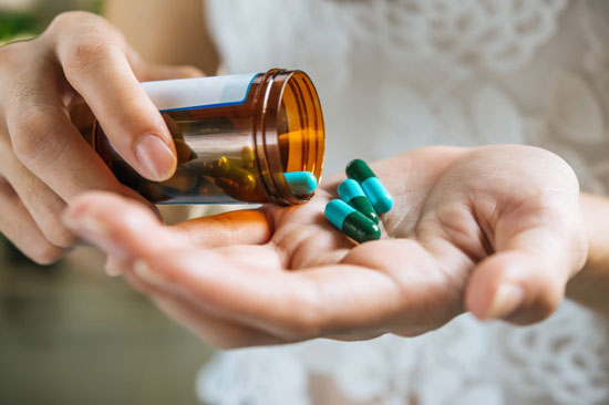 mujer poniendo varias pastillas de un botecito en la mano