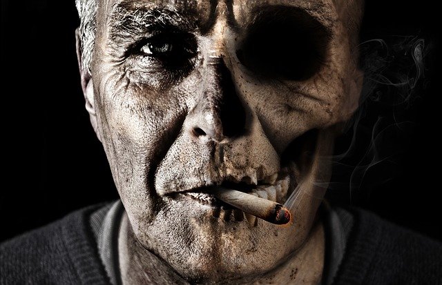 hombre con un cigarro de marihuana, la mitad de la cara es una calavera