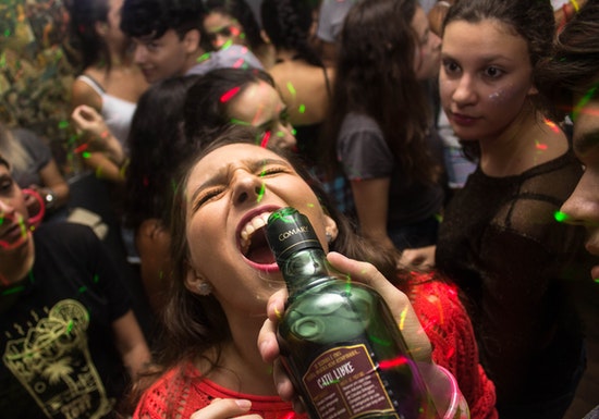 mujer en una fiesta tomando alcohol directamente de una botella