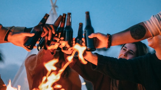 Grupo de amigos en una fogata tomando cerveza