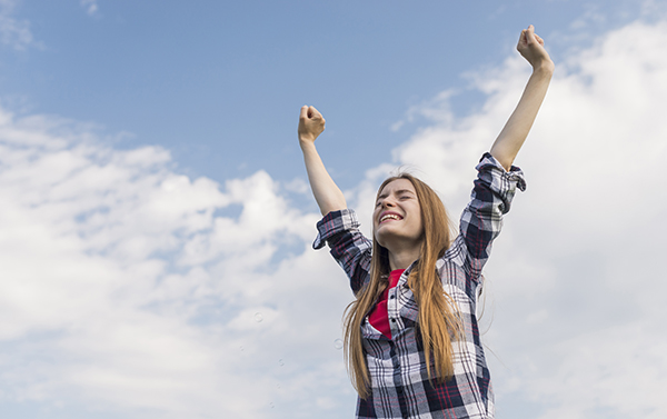 mujer feliz levanta los brazos en señal de triunfo