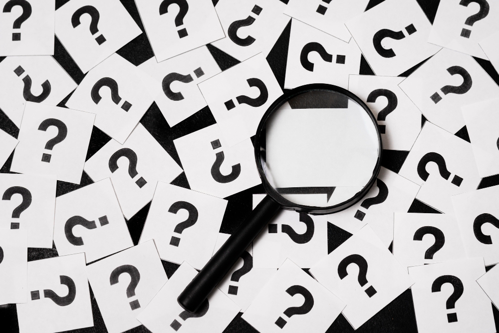 Signos de interrogación con una lupa encima.